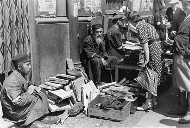 A woman purchases firewood from a street vendor in the Warsaw ghetto
